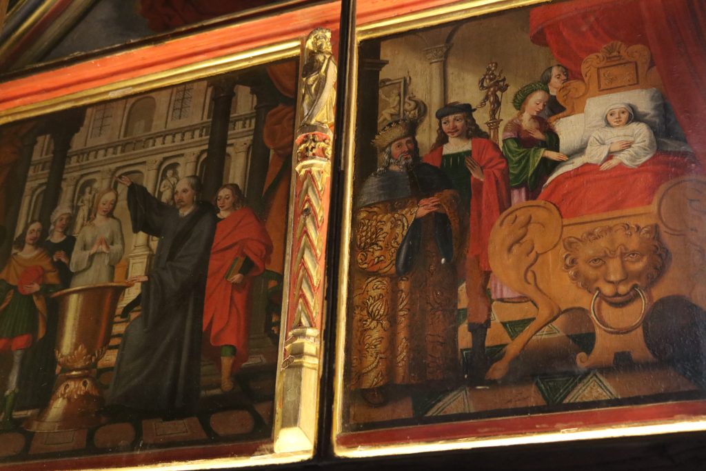 The color photo shows an early modern painting in rich but muted colors, showing a woman at the center of two scenes. On the light, the woman, St Dymphna is standing and man holds his hand above her head. On the right, she lies in bed, surrounded by other people. 
