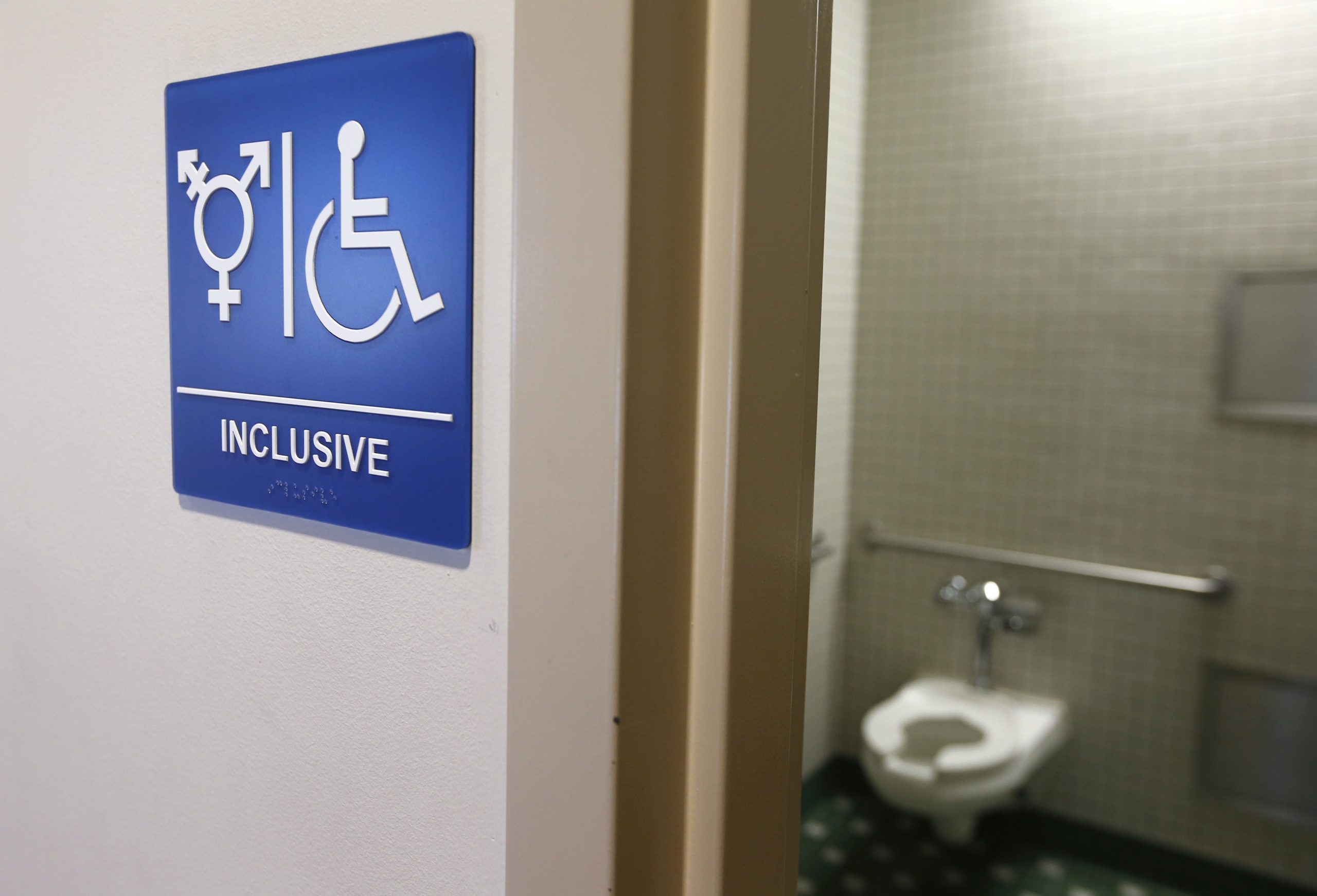 Photo of bathroom with sign that says “Inclusive” and has trans and disability icon