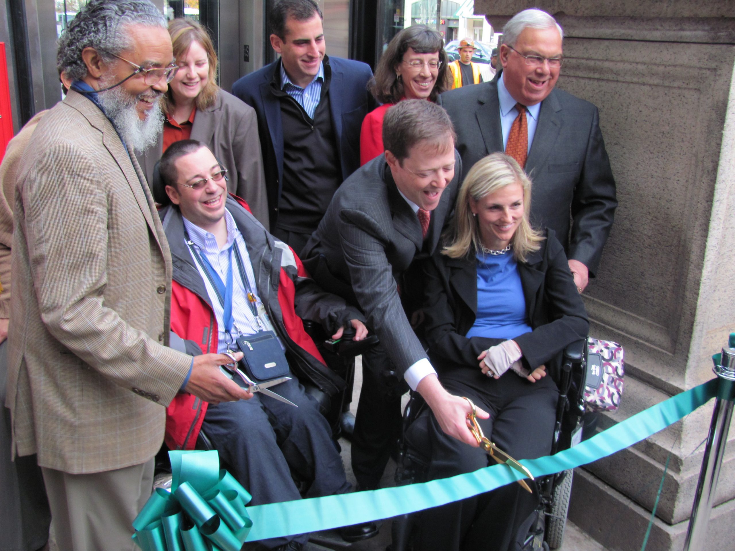 A group of predominantely white people at a ribbon cutting