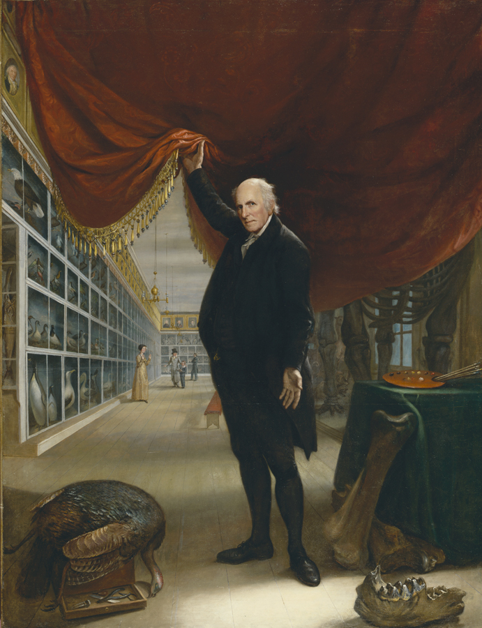 Oil painting of balding grey haired white man in a long black coat lifting a red curtain to reveal a scene of a museum of patrons viewing images of wildlife and skeletons. In the foreground are bones, a bird, a toolbox and a table with a green tablecloth and an artist's palette. 